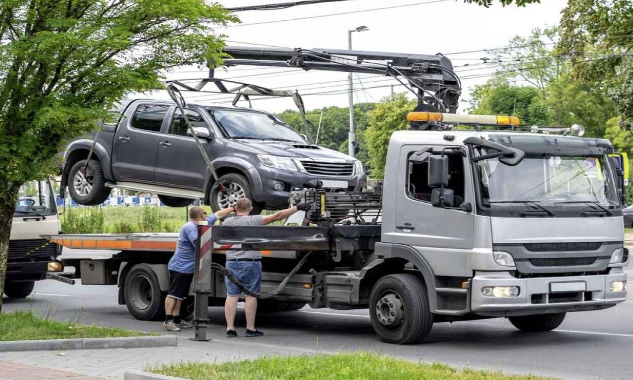 Flatbed tow truck safely loading a pickup truck on city street