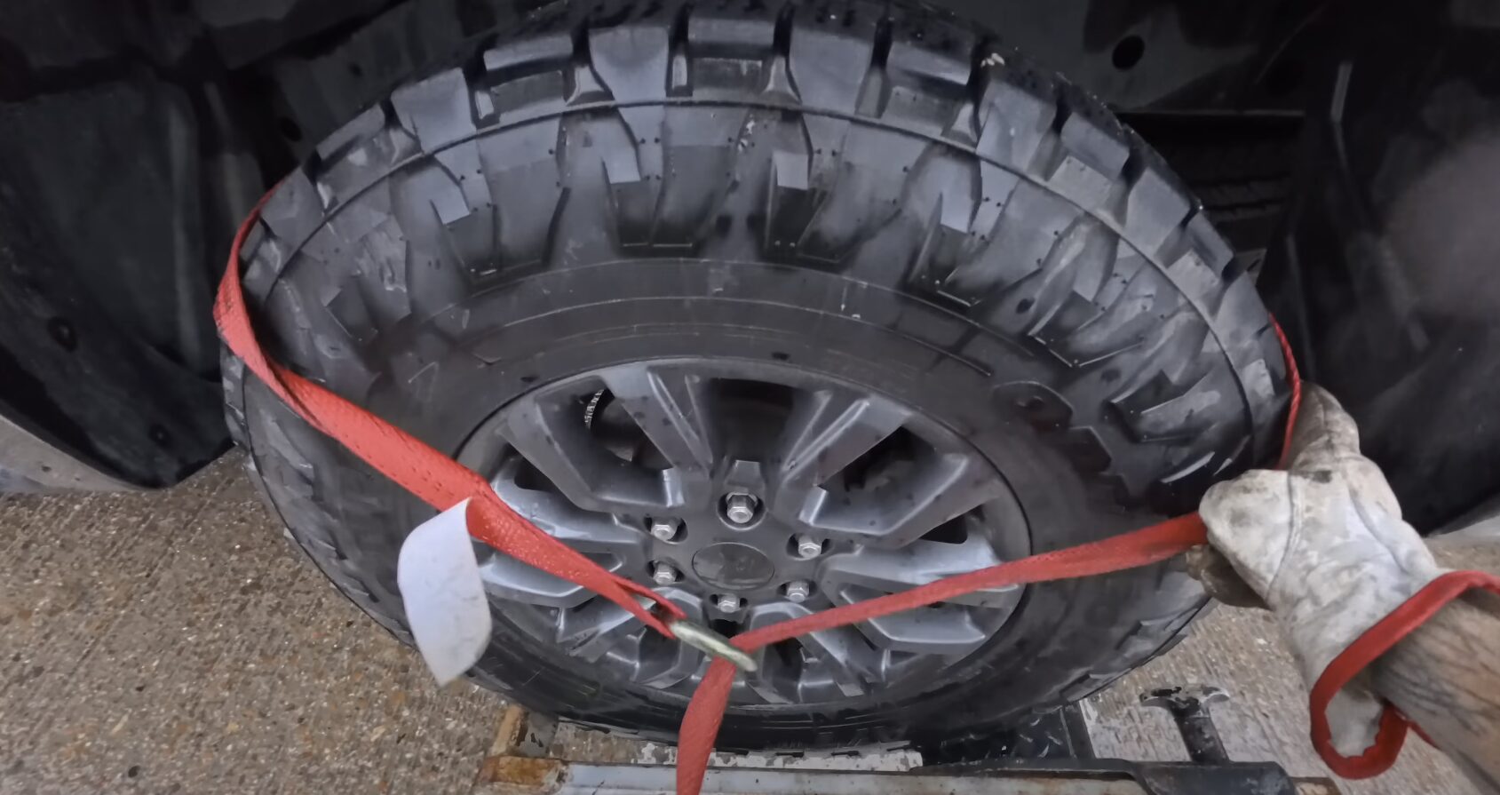 Professional Roadside Assistance Services Car wheel secured with red towing straps on flatbed truck for safe transport